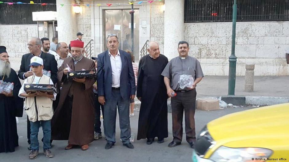 رجال دين مسيحيون ومسلمون وسامريون يوزعون الماء والتمر على الصائمين المتأخرين عن الوصول إلى مائدة الإفطار